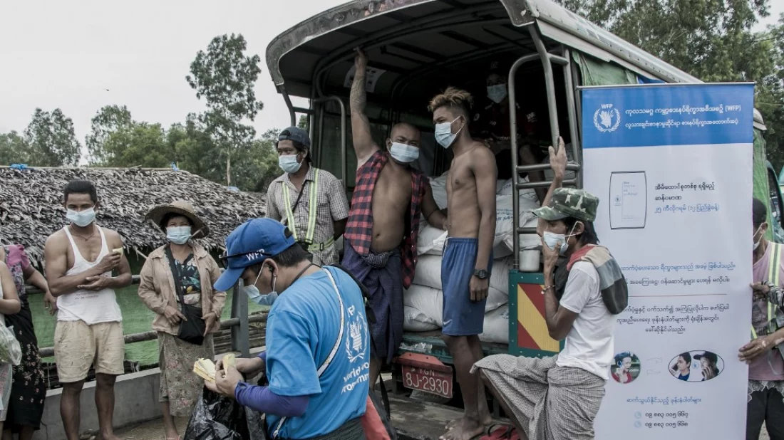 People wait to receive bags of rice distributed by the World Food Programme (WFP)